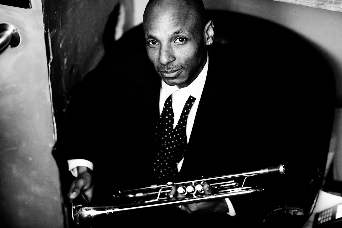 A trumpeter in a suit holding his horn, in black and white