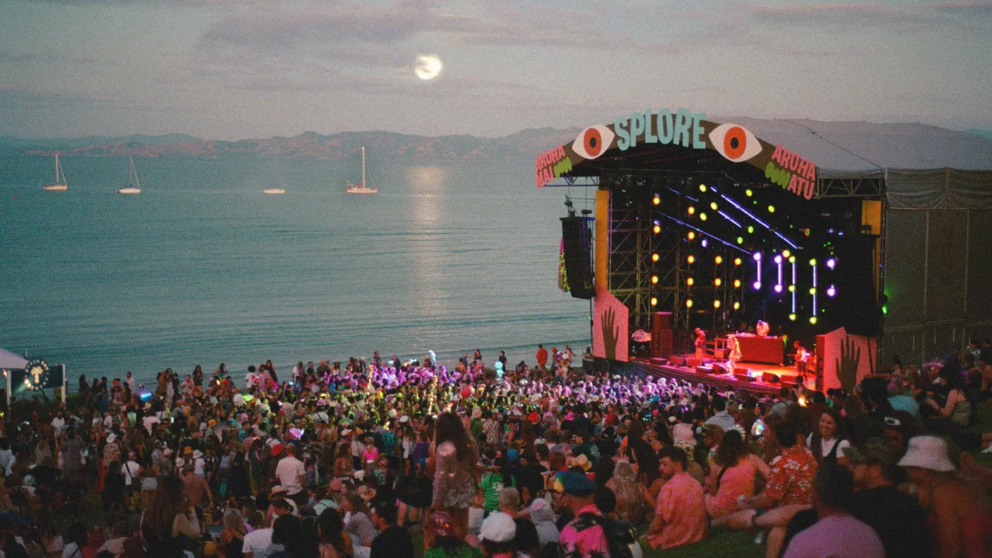A crowd facing a seaside stage under the moon
