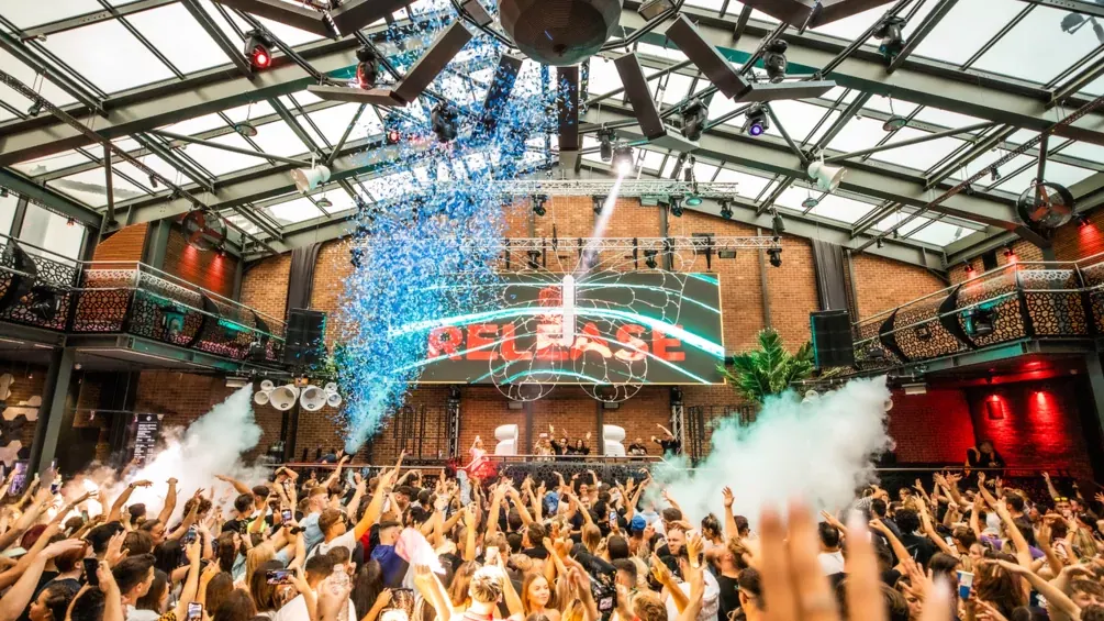 Dancers under a glass roof with smoke jets at Studio 338