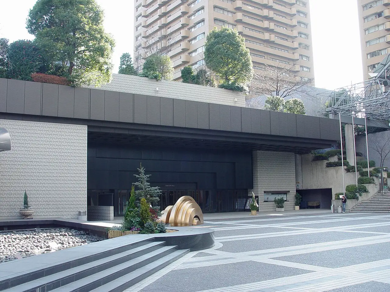 A broad plaza in front of a low, dark-roofed modern building