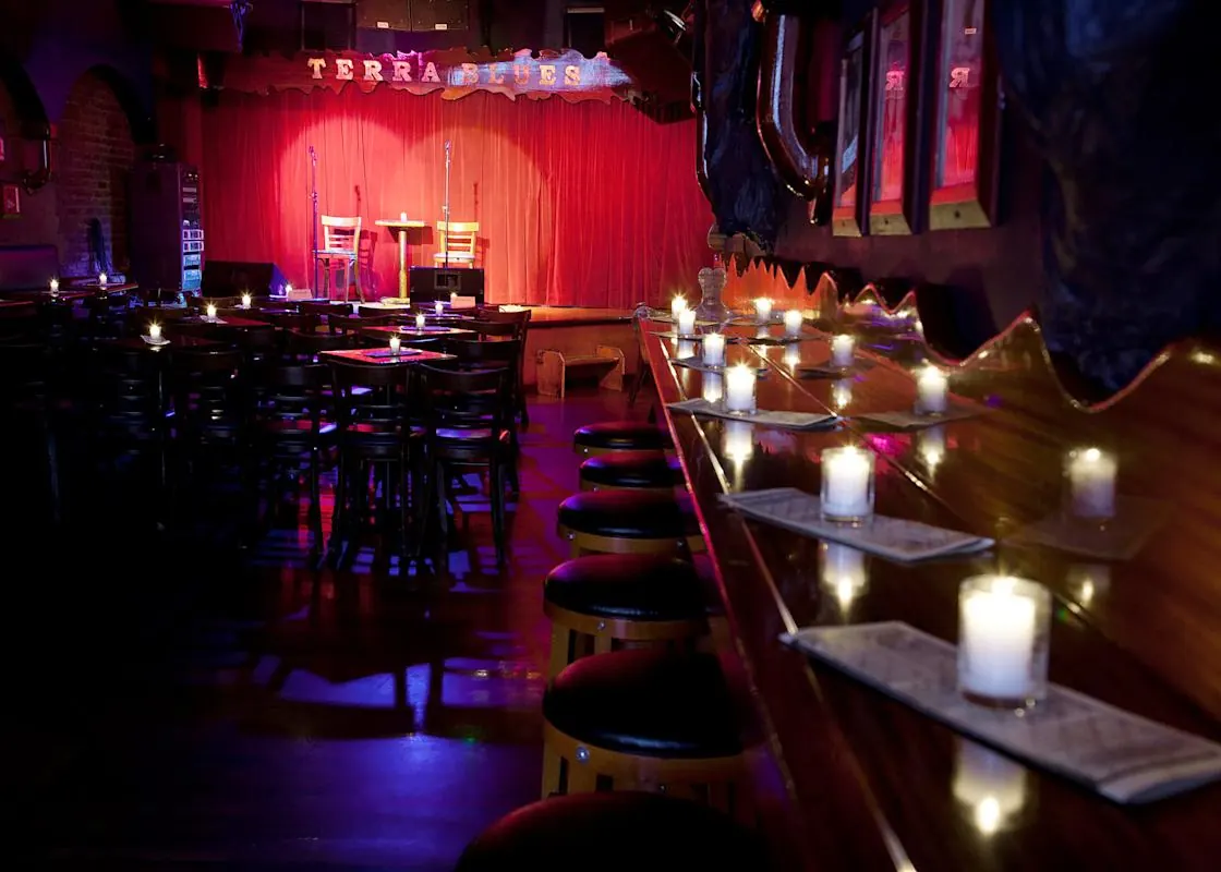 A candle-lit bar counter leading to the red stage