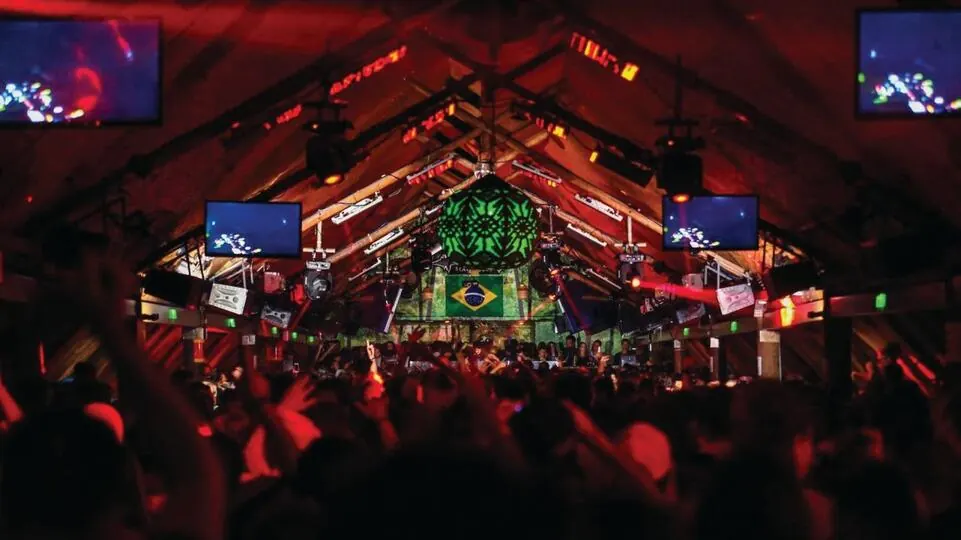A dancefloor crowd in a timber-framed room lit red