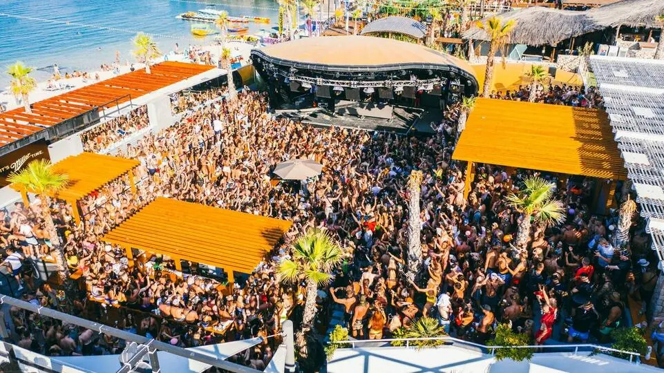 An aerial view of a crowd on the beach in orange light