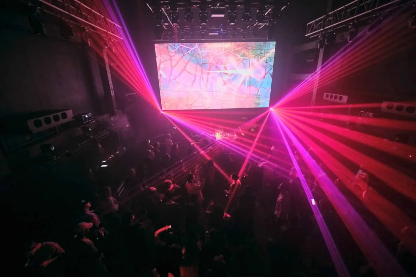 Pink laser beams fanning across a dark dance floor at Womb