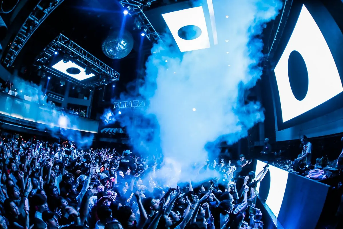 A crowd under blue and white lights and screens