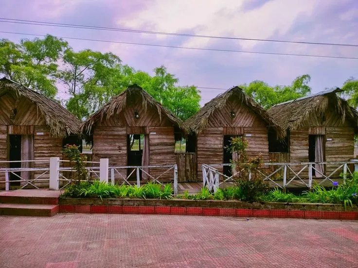 A row of thatched bamboo huts on a paved yard