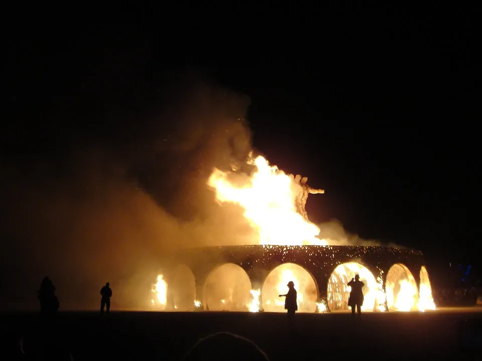 A large fire burning behind a row of arches at night