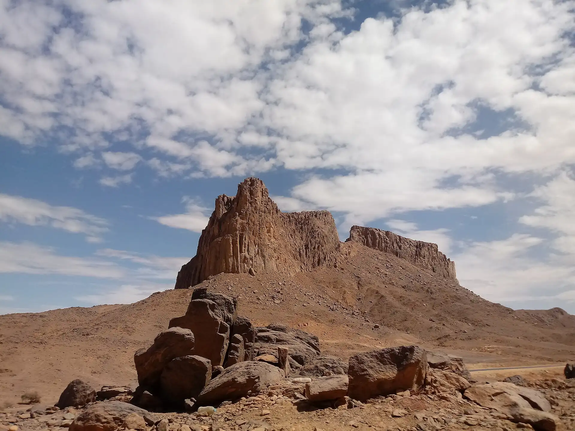 A rocky peak and boulders under a cloudy sky in the Hoggar