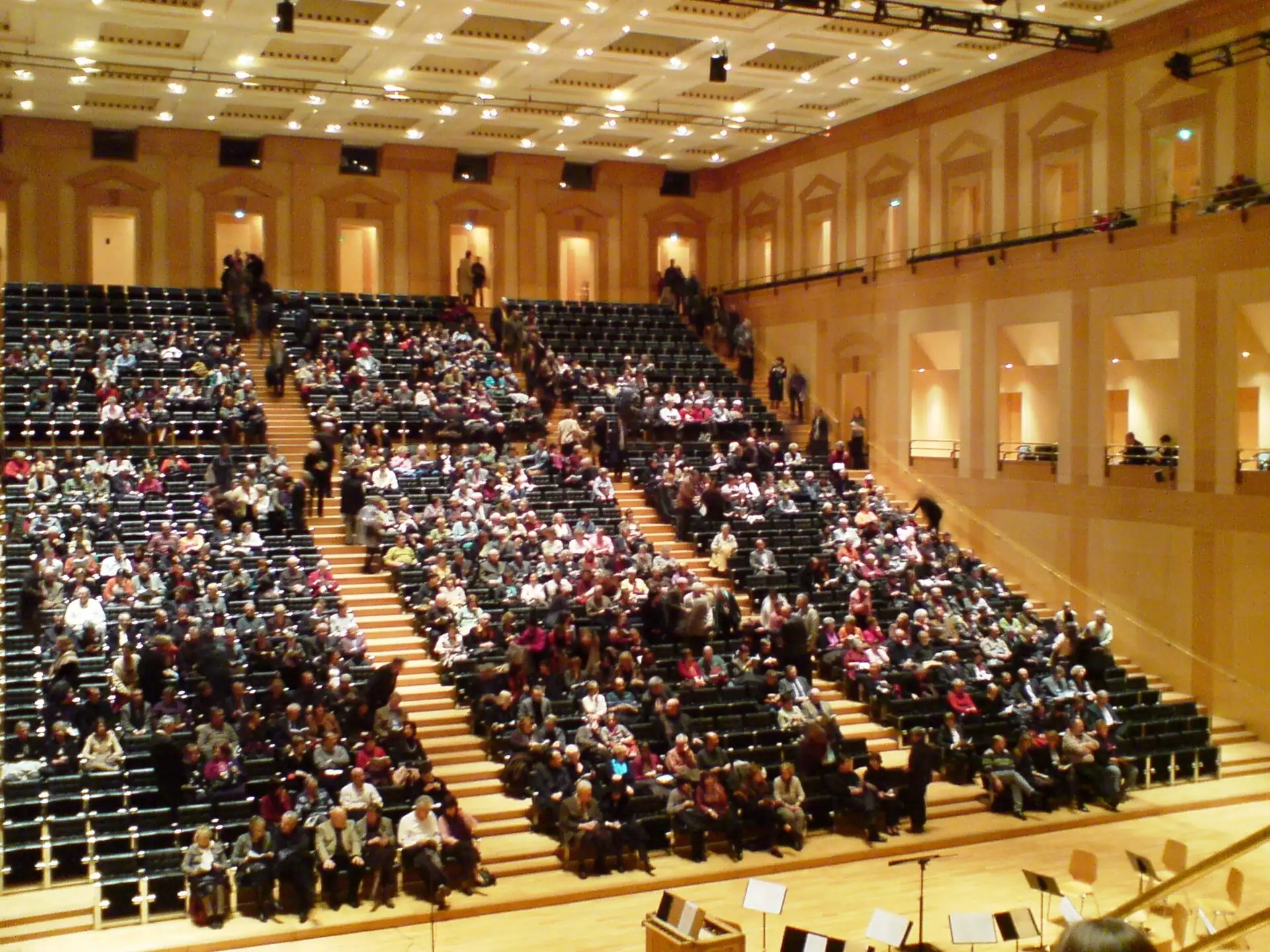 Tiered seating full of audience in the wood-lit hall of the Arsenal