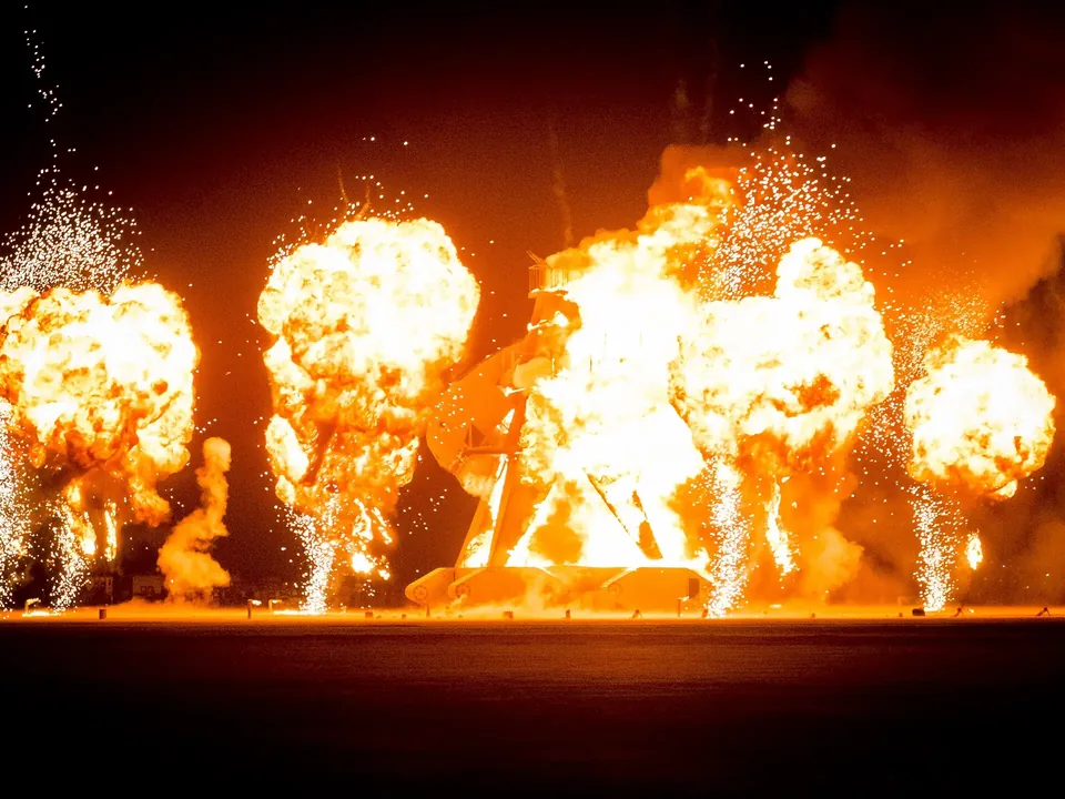 Fire bursting from a tall structure in the desert at night