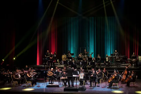 An orchestra on stage under teal and red lights at the Cairo Opera House