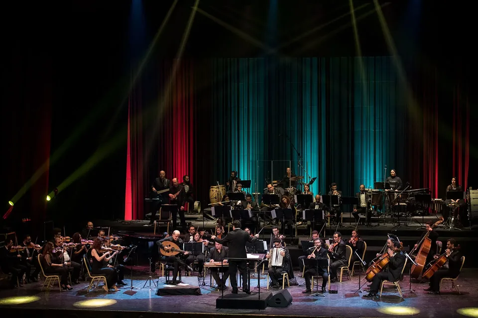 An orchestra on stage under teal and red lights at the Cairo Opera House