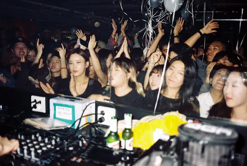 Hands raised in the crowd around a DJ booth at Cakeshop