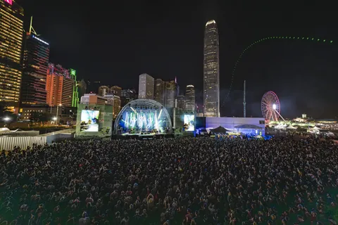 A crowd in front of a stage against the Hong Kong skyline at night