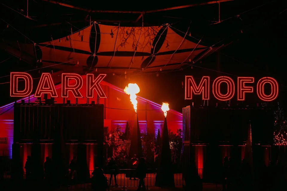 The red Dark Mofo sign glowing above a dark space with flames