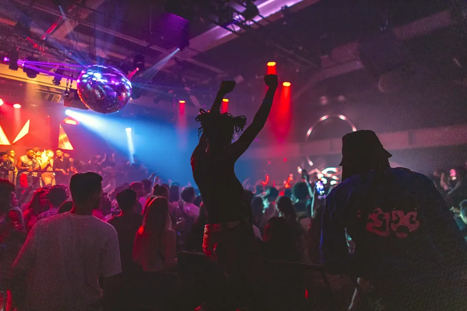 A crowd with raised hands under red and blue lights