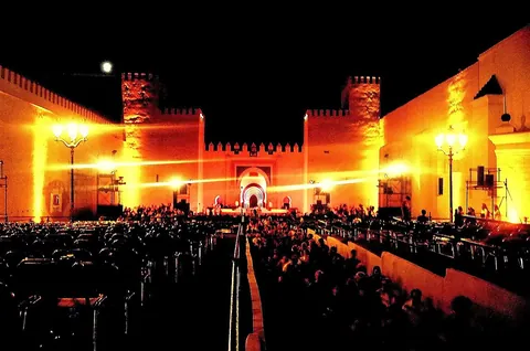 A night-time concert crowd in front of a floodlit fortified gate