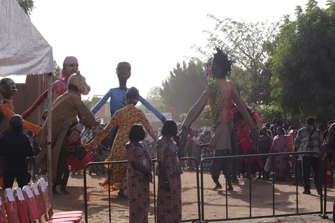 Giant costumed puppets and a crowd behind a barrier