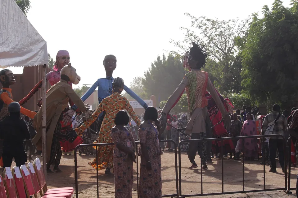 Giant costumed puppets and a crowd behind a barrier