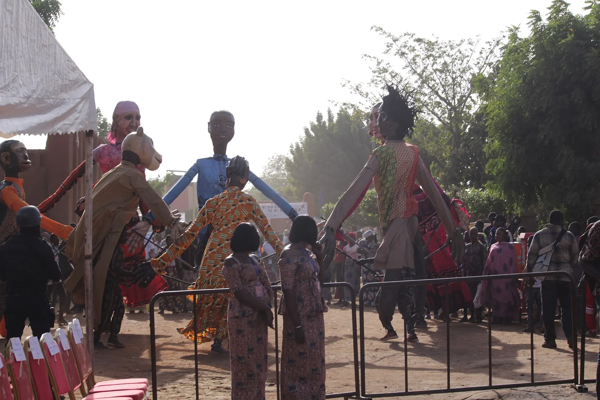 Giant costumed puppets and a crowd behind a barrier