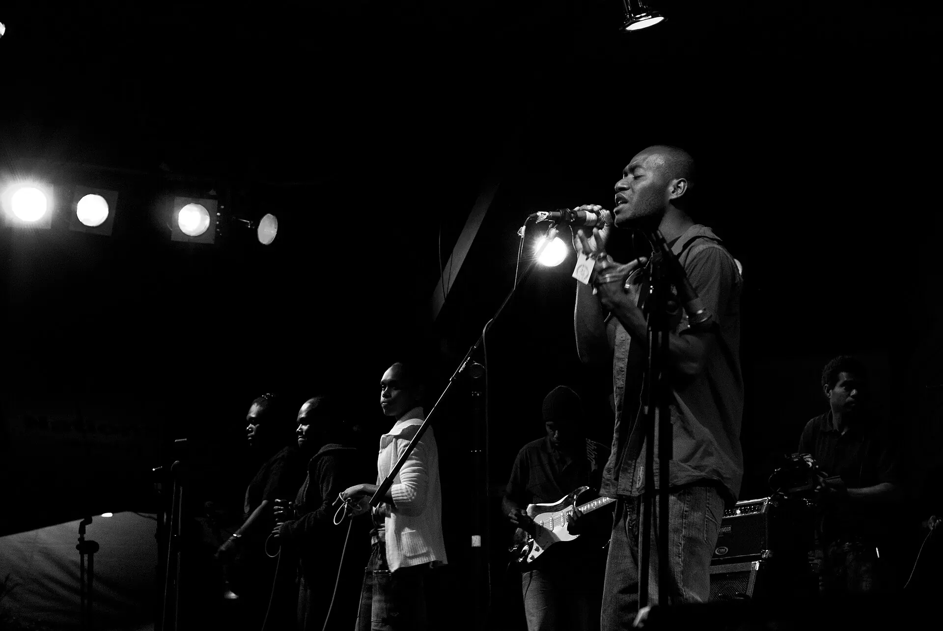 A black-and-white shot of a singer at a microphone with a band behind, at Fest Napuan
