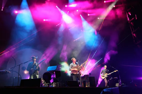 A band on stage under pink and blue lights at Fuji Rock