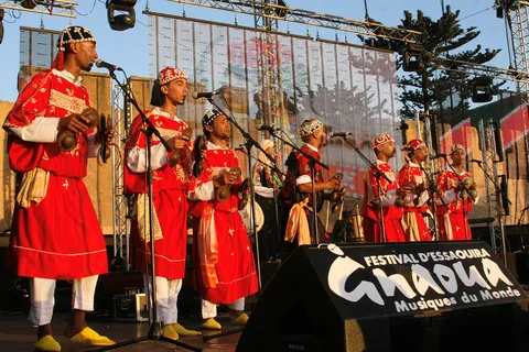 Musicians in red robes performing under the Gnaoua festival banner