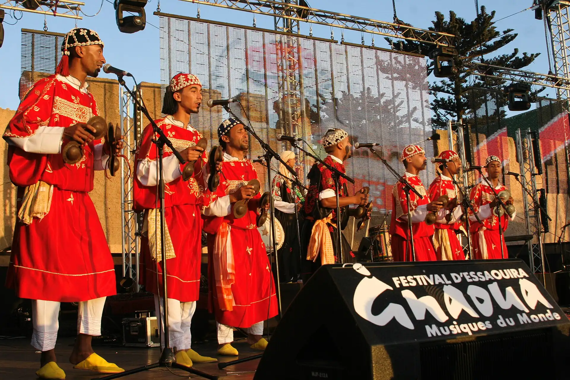 Musicians in red robes performing under the Gnaoua festival banner