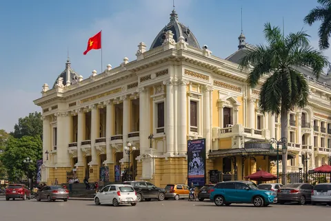 The cream-coloured colonial facade of the Hanoi Opera House with palm trees
