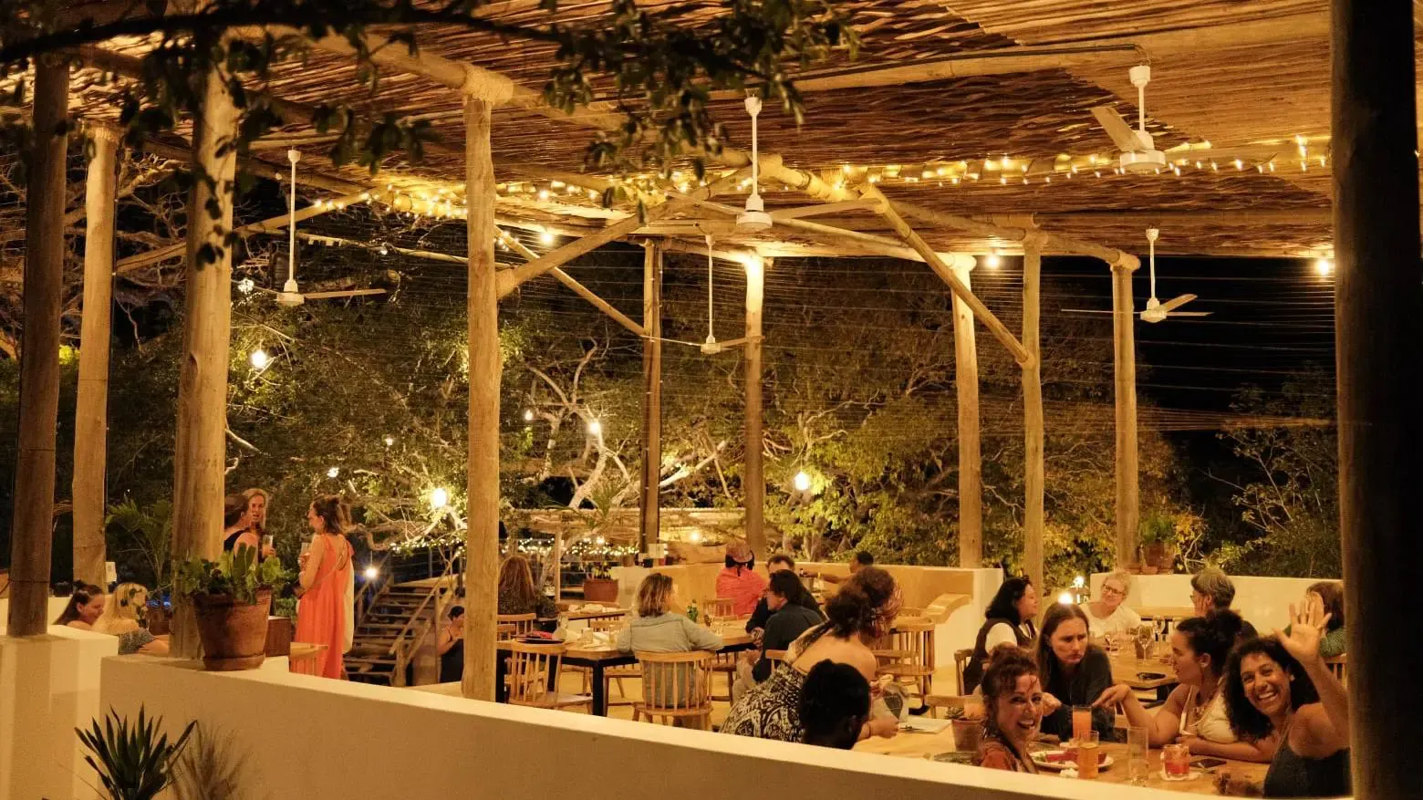 A lantern-lit open-air restaurant with people at tables at night