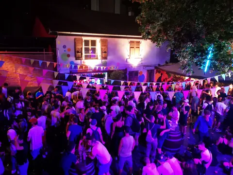 A crowd dancing in purple light at La Gravière