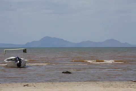 The shore of Lake Turkana with a boat and distant hills