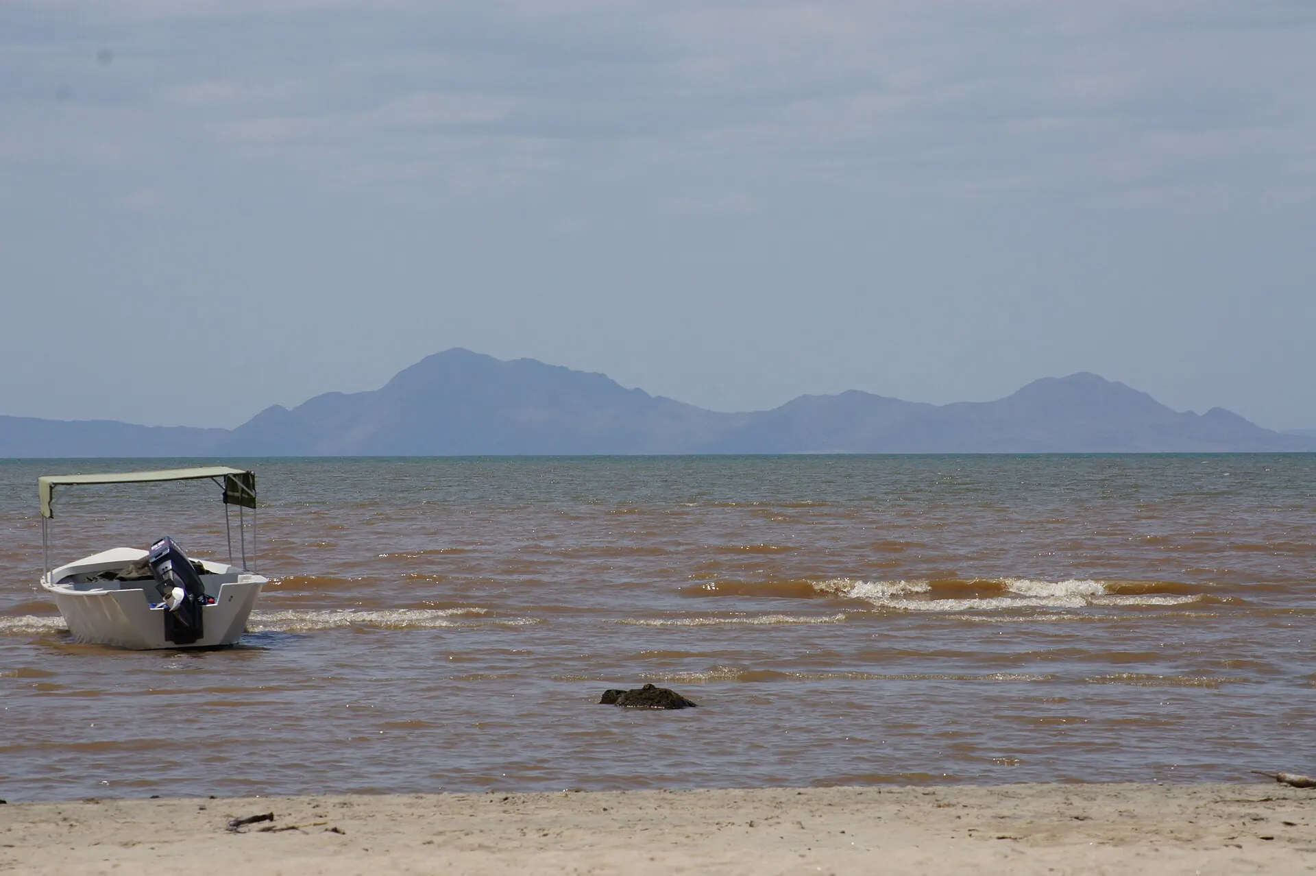 The shore of Lake Turkana with a boat and distant hills