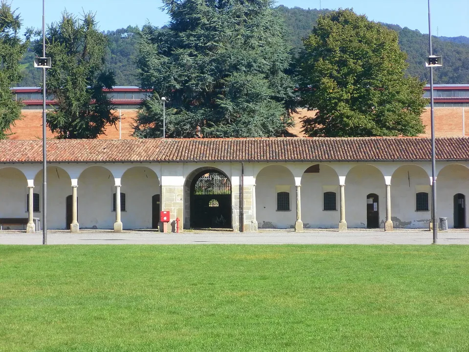 The arcade of the Lazzaretto in Bergamo with a lawn in front and wooded hills behind