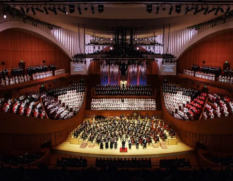 An orchestra on stage in Lotte Concert Hall, with terraces of seats around it
