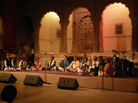 Turbaned musicians seated on a low stage before scalloped sandstone arches at Mehrangarh Fort during Jodhpur RIFF in 2009