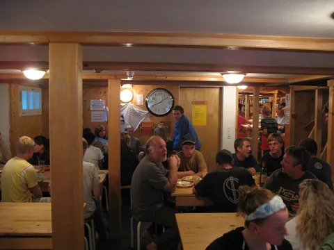 Guests at wooden tables in the Mountain Hostel dining room in Gimmelwald