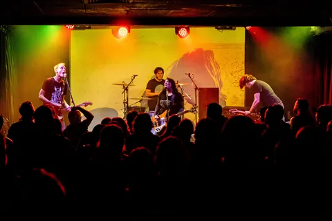 A band playing on a stage lit in yellow and green at Northcote Social Club