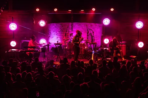 A band on a stage under magenta lights in front of a crowd at Pappy and Harriet's
