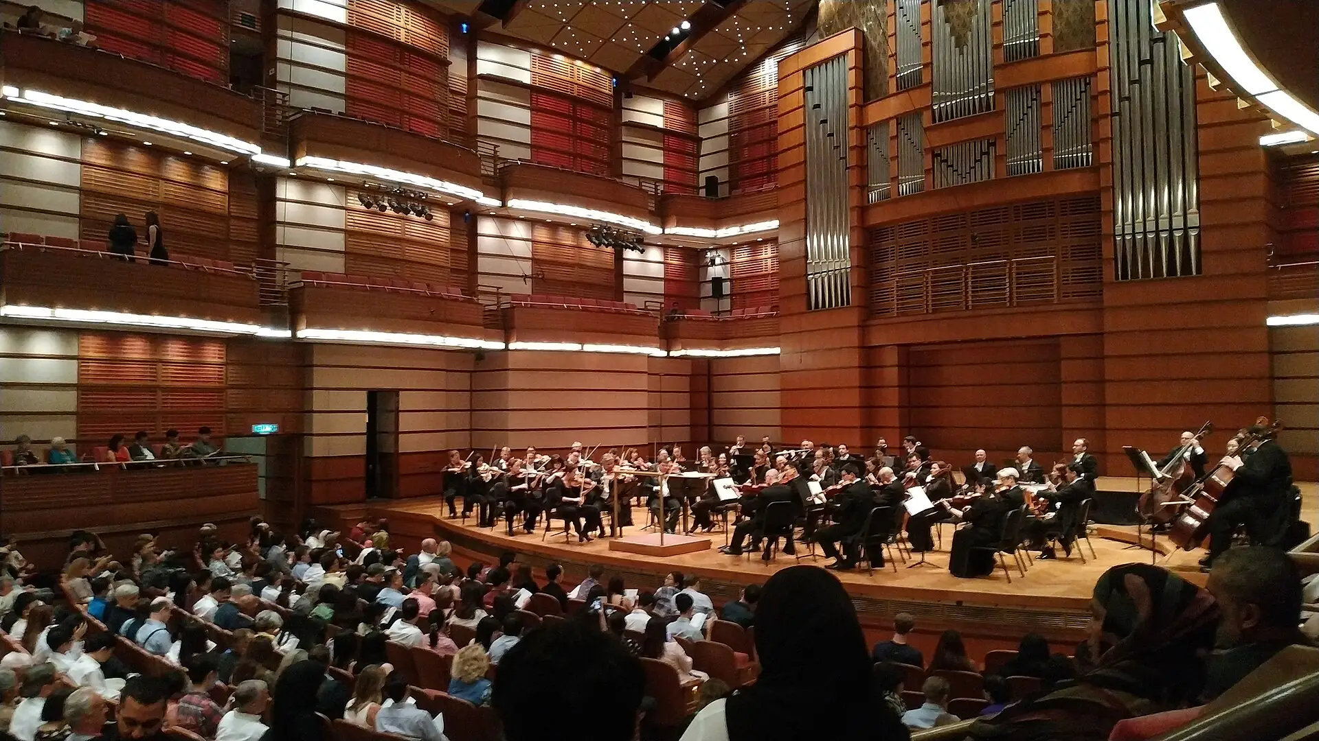 An orchestra performing in the Petronas Philharmonic Hall with audience seating in the foreground