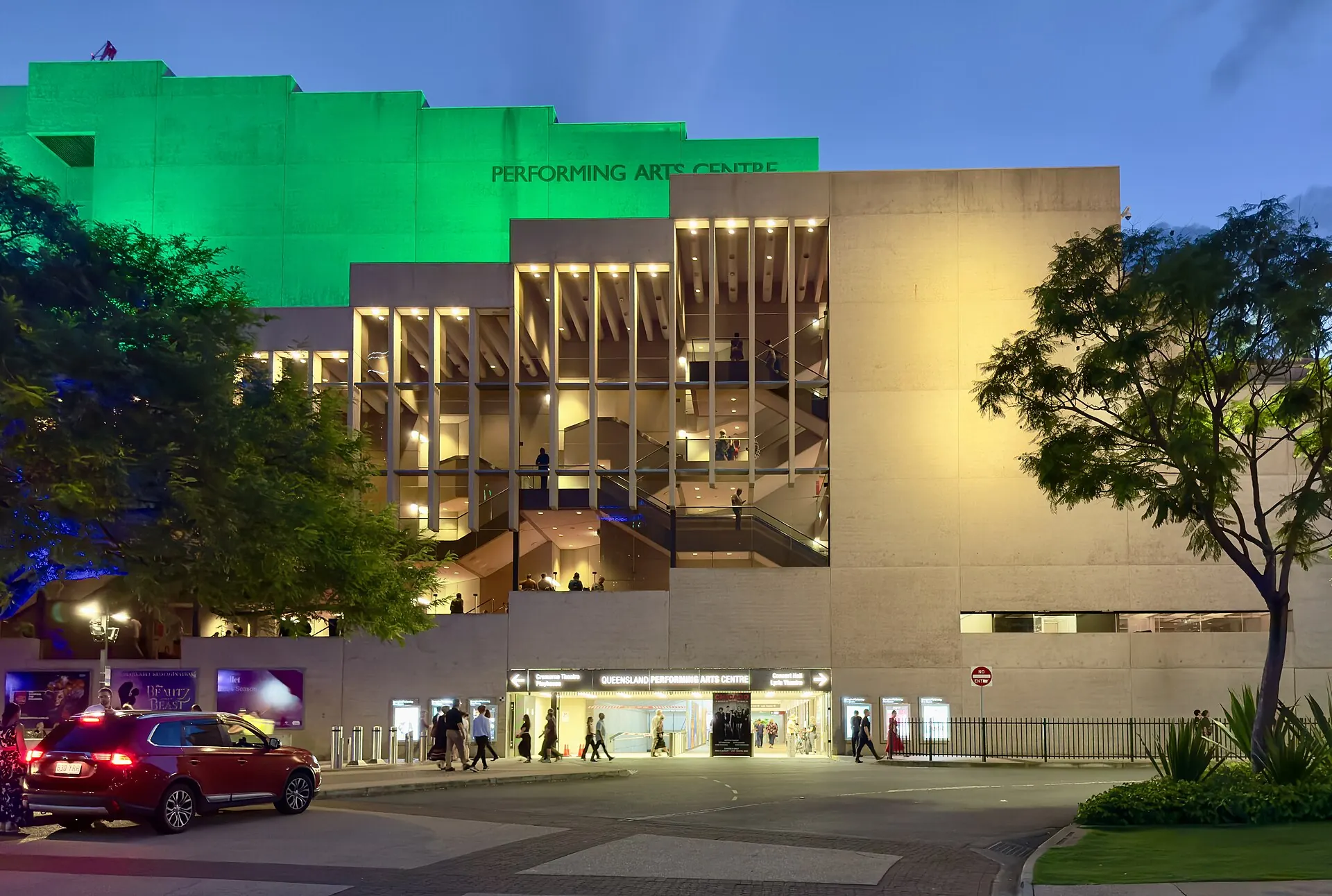 The Queensland Performing Arts Centre lit at night, with a green-lit top storey