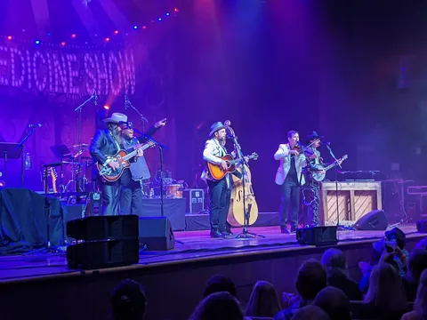 A band performing on the lit stage of the Ryman Auditorium