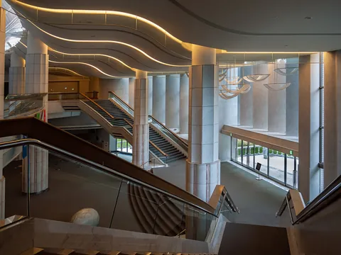A curved staircase and glass wall inside the Sapporo Kitara foyer