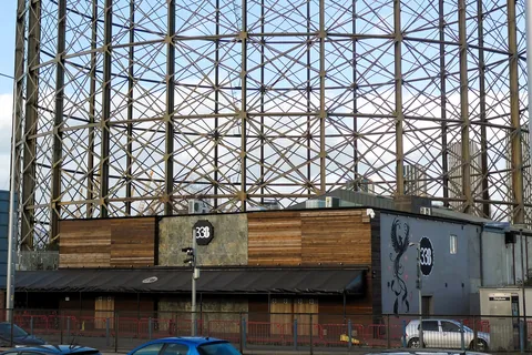 A gasholder-style steel frame beside the low building of Studio 338