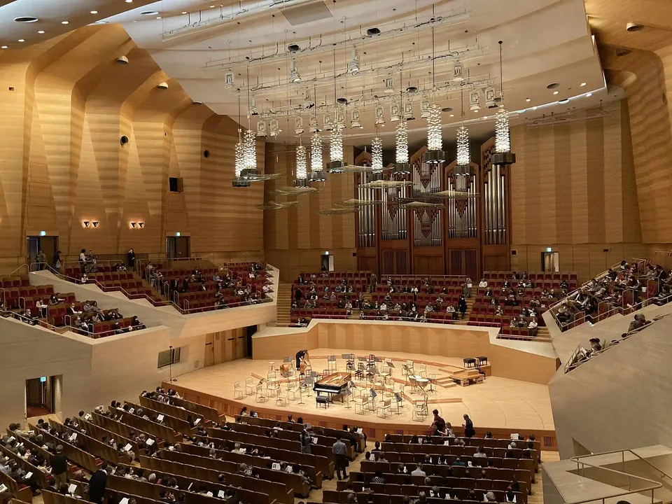 An orchestra on stage in Suntory Hall, with blocks of seats rising around the platform
