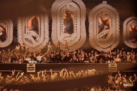 A crowd in front of a stage framed by huge carved white letters