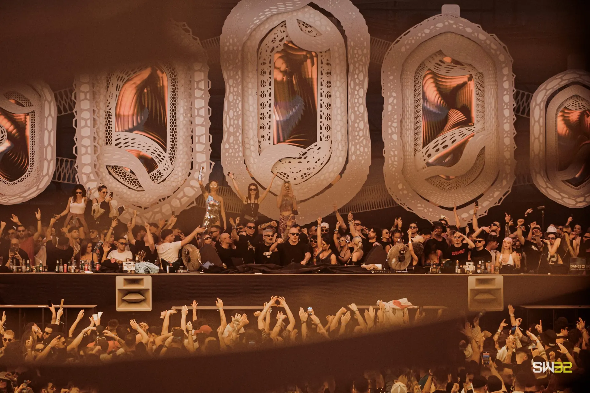 A crowd in front of a stage framed by huge carved white letters