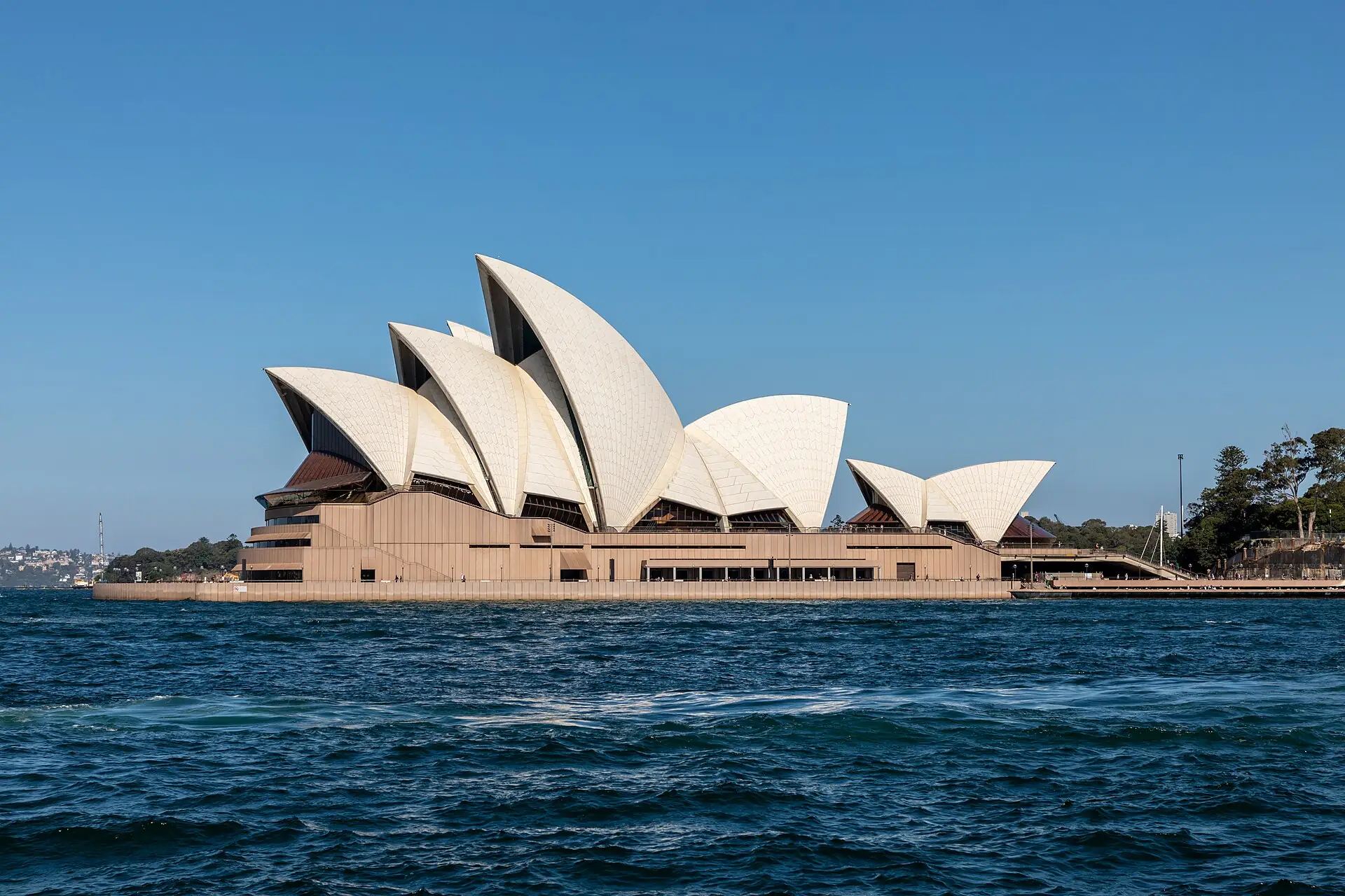 The Sydney Opera House sails across the harbour under a blue sky