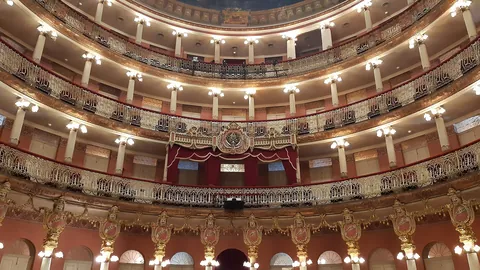 Tiers of gilded balustrades, white columns and globe lights climbing the horseshoe auditorium of Teatro Amazonas in Manaus