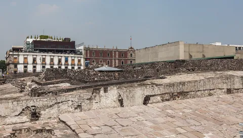 Excavated Aztec ruins of the Templo Mayor with colonial buildings behind